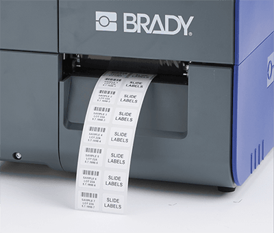 Zadrukowane etykiety wychodzące z drukarki Brady i7500 bez widocznych strat materiału.