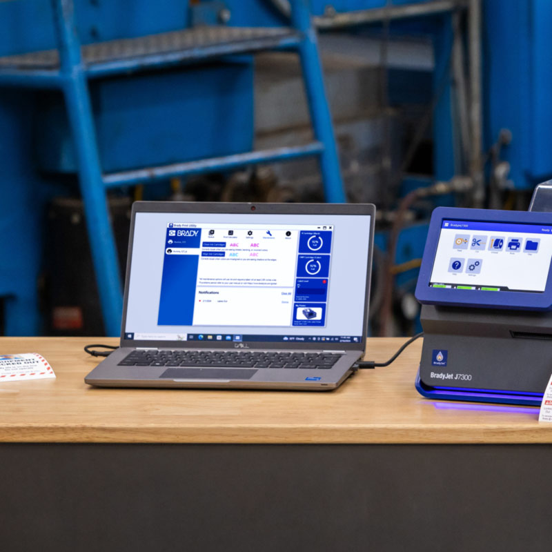 Laptop podłączony do drukarki J7300 z wyświetlonym ekranem aplikacji Brady Workstation.