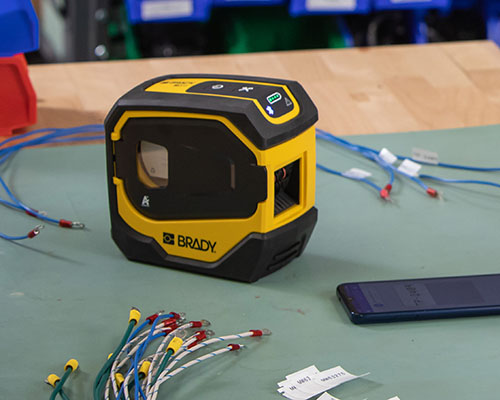Drukarka M511 z przewodami oznaczonymi etykietami i telefonem komórkowym.