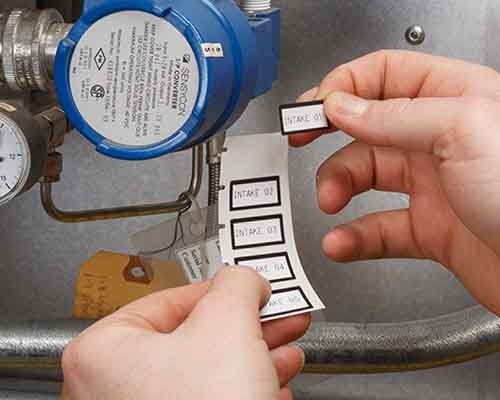 Osoba naklejająca na maszynę etykiety wydrukowane na drukarce M610.