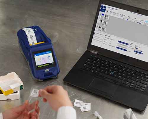 Osoba nakładająca etykietę wydrukowaną na drukarce M611 na szkiełko laboratoryjne.